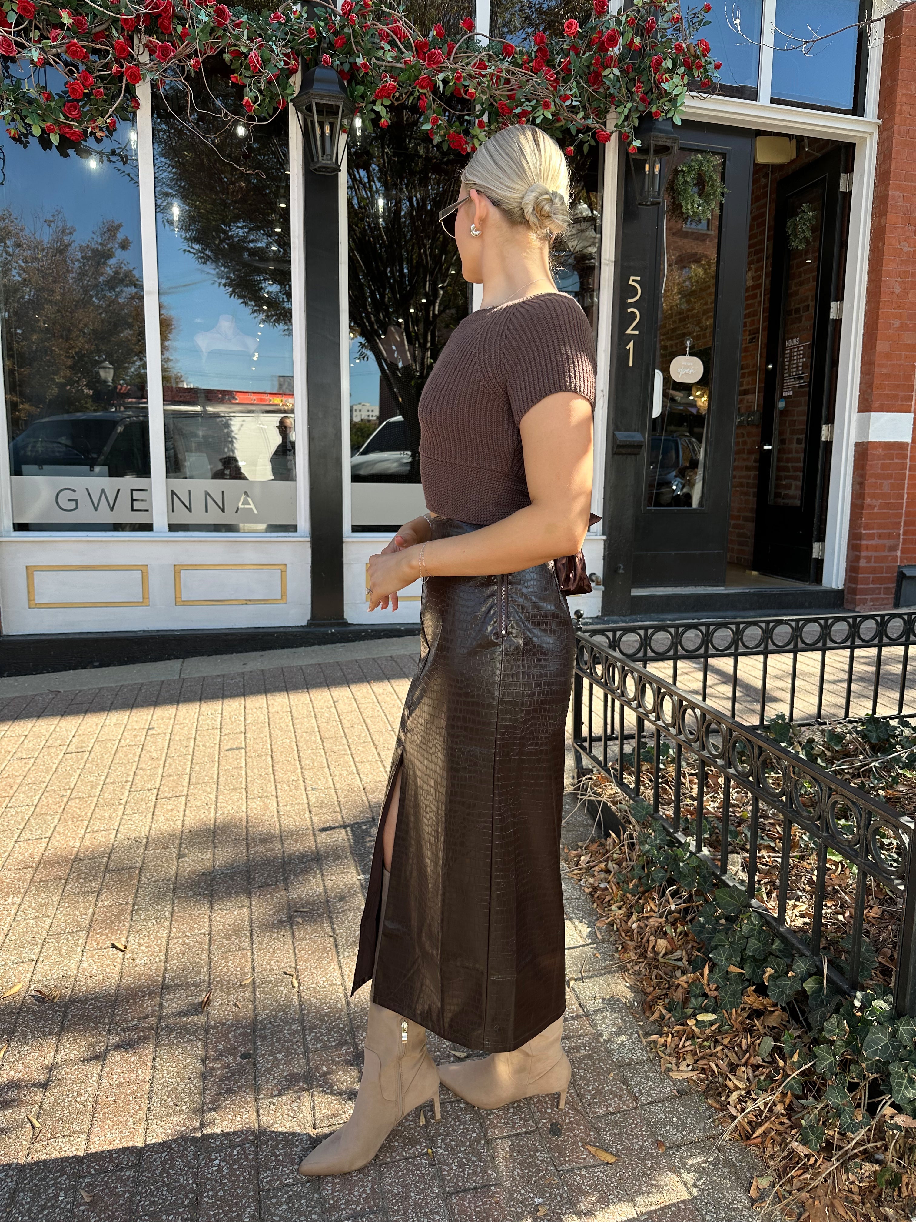 Woman wearing brown knit short sleeve sweater top with bow back.
