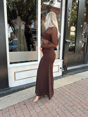 Woman wearing a long sleeve brown sheer maxi dress.