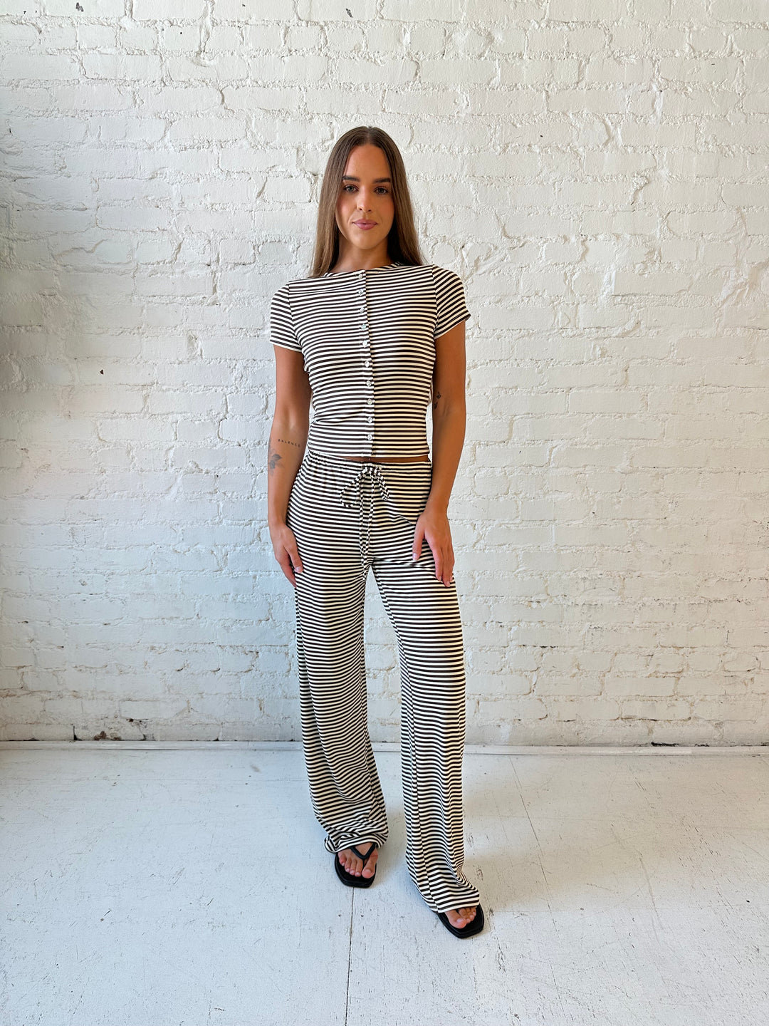 Woman wearing brown and ivory striped two piece lounge set with button down short sleeve top.