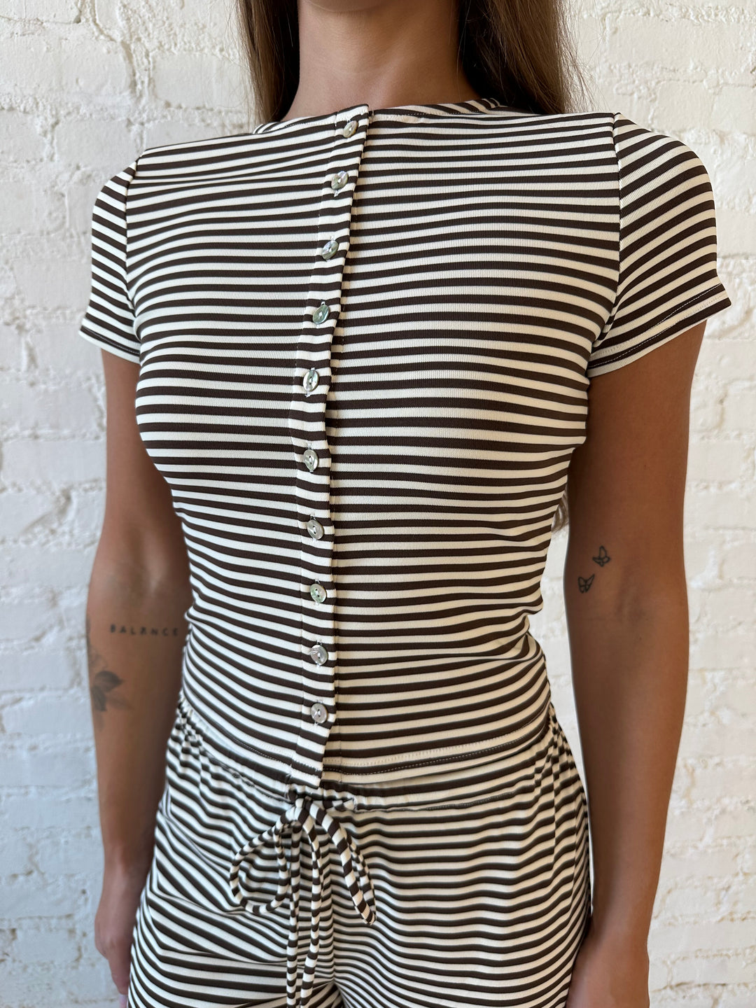Woman wearing brown and ivory striped two piece lounge set with button down short sleeve top.