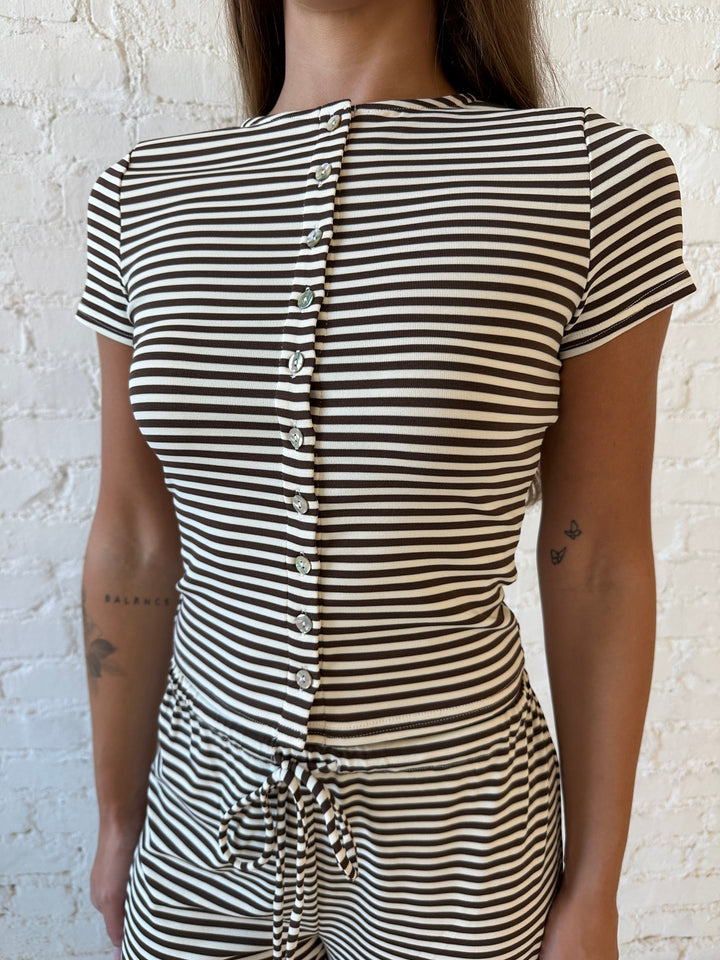 Woman wearing brown and ivory striped two piece lounge set with button down short sleeve top.
