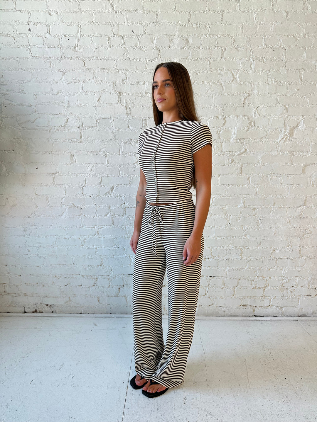 Woman wearing brown and ivory striped two piece lounge set with button down short sleeve top.