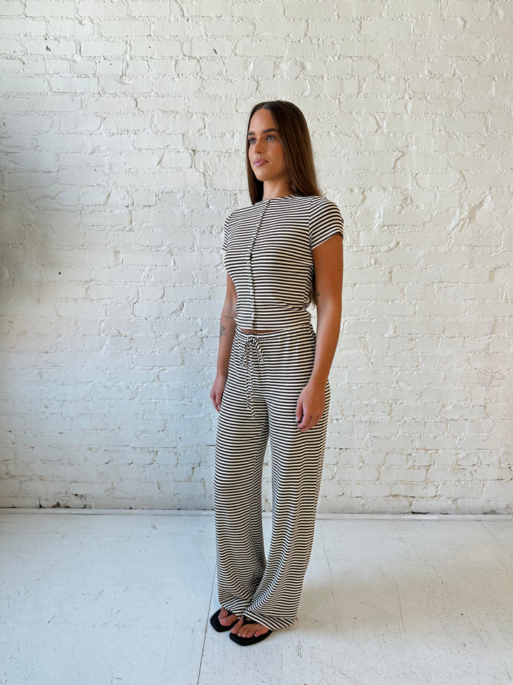 Woman wearing brown and ivory striped two piece lounge set with button down short sleeve top.