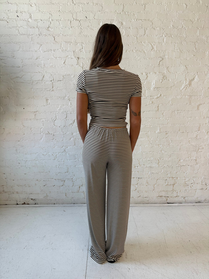 Woman wearing brown and ivory striped two piece lounge set with button down short sleeve top.