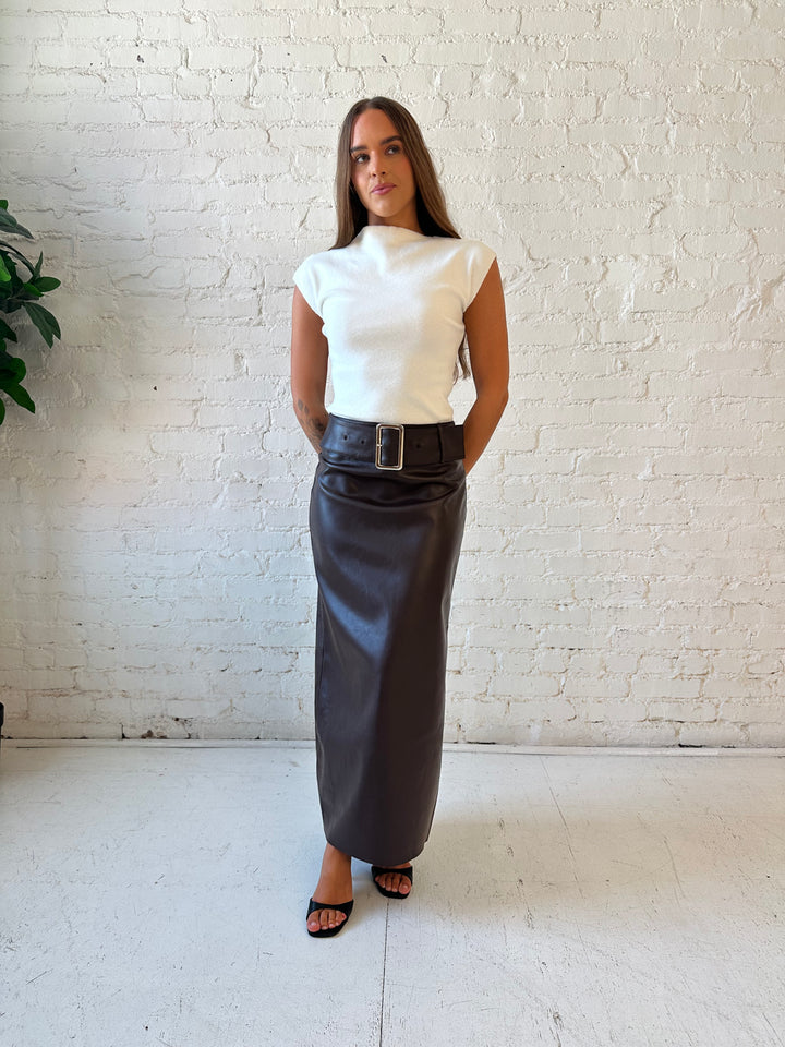 Woman wearing dark brown faux leather midi skirt with belted midsection and white cap sleeve top.