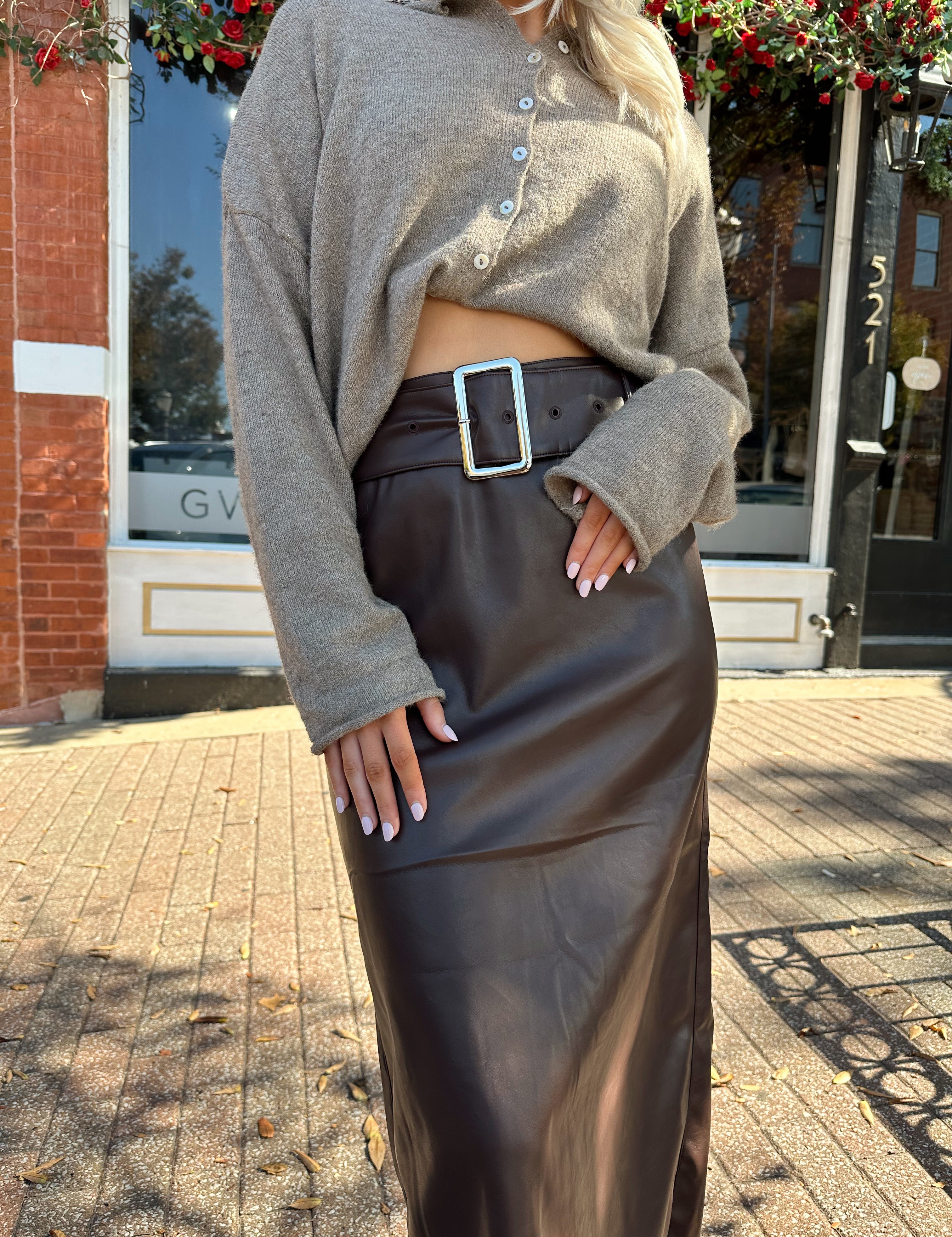 Woman wearing dark brown belted leather midi skirt with mocha knit cardigan.