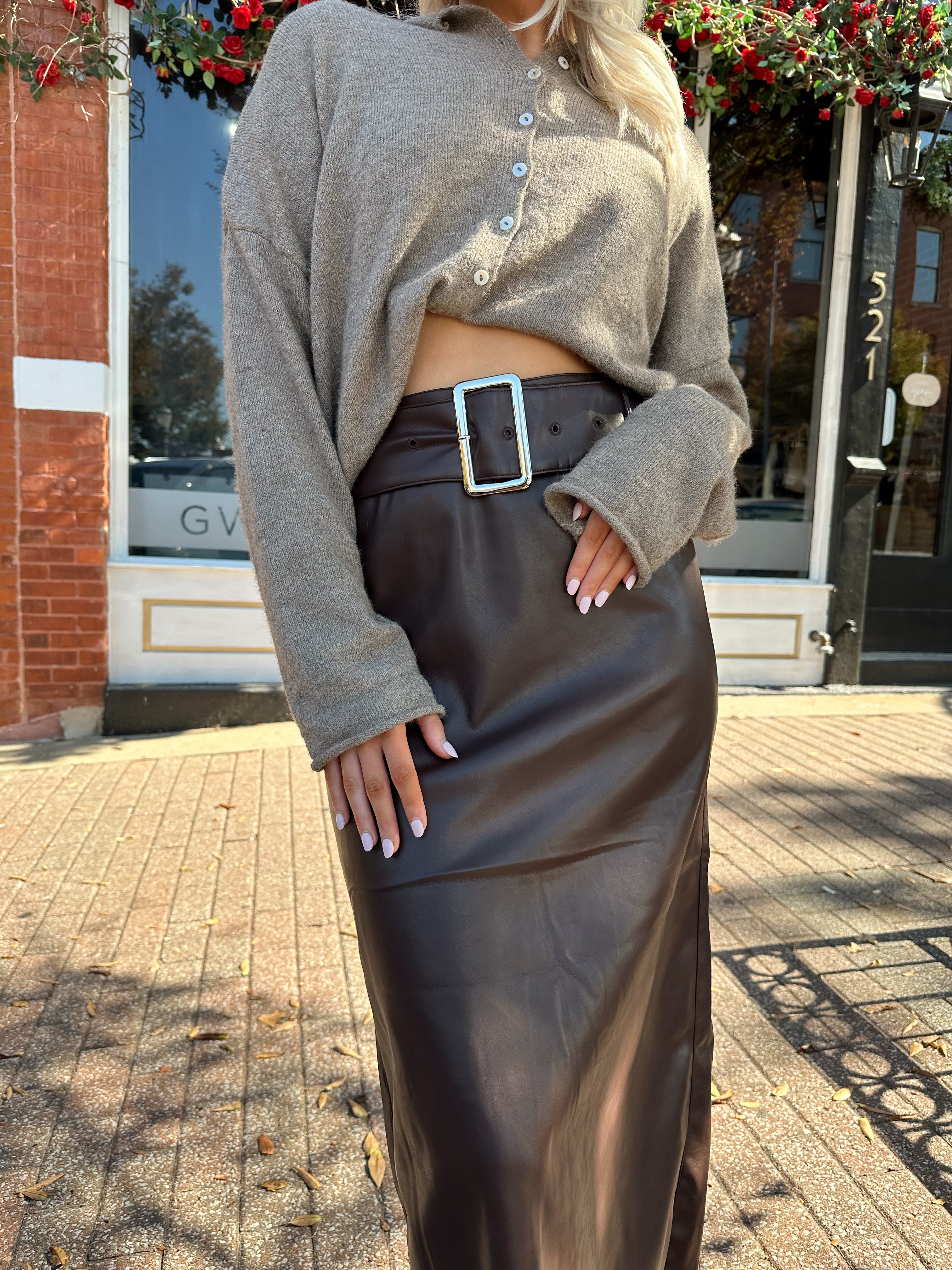 Woman wearing dark brown belted leather midi skirt with mocha knit cardigan.