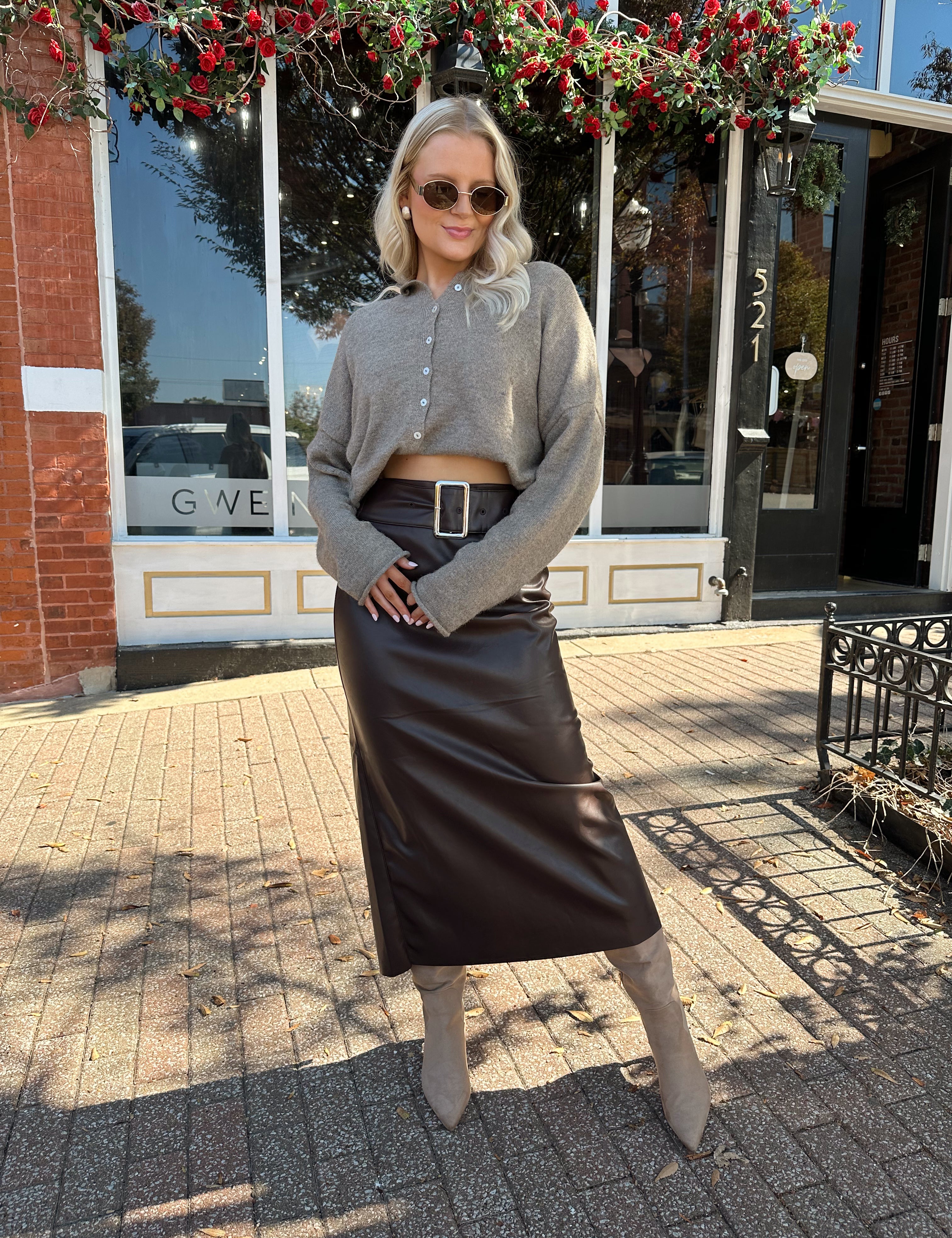 Woman wearing dark brown belted leather midi skirt with mocha knit cardigan.
