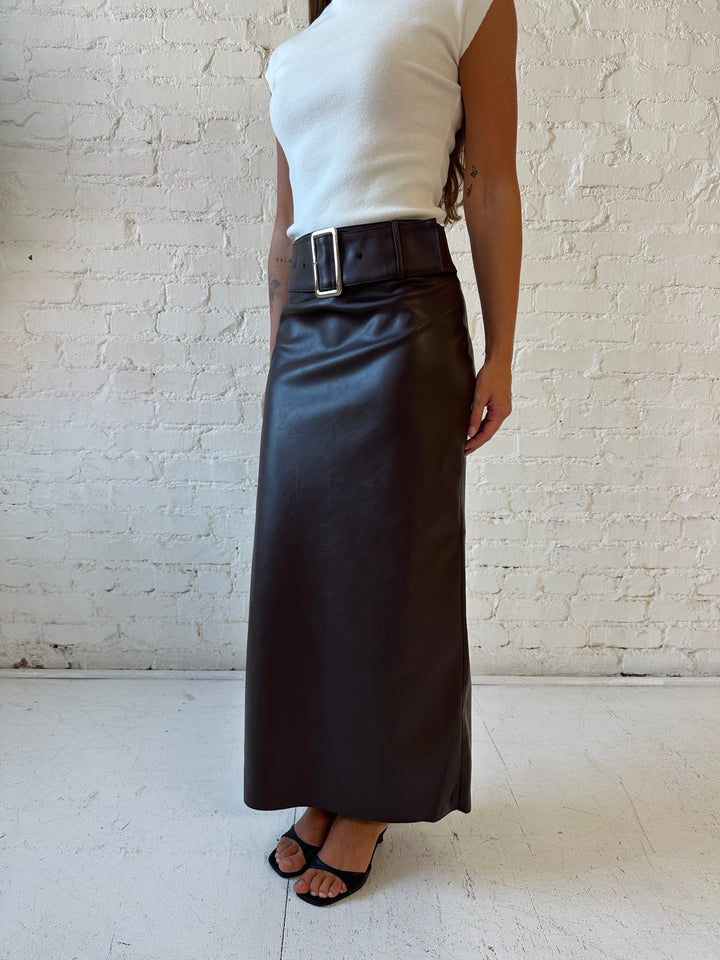 Woman wearing dark brown faux leather midi skirt with belted midsection and white cap sleeve top.