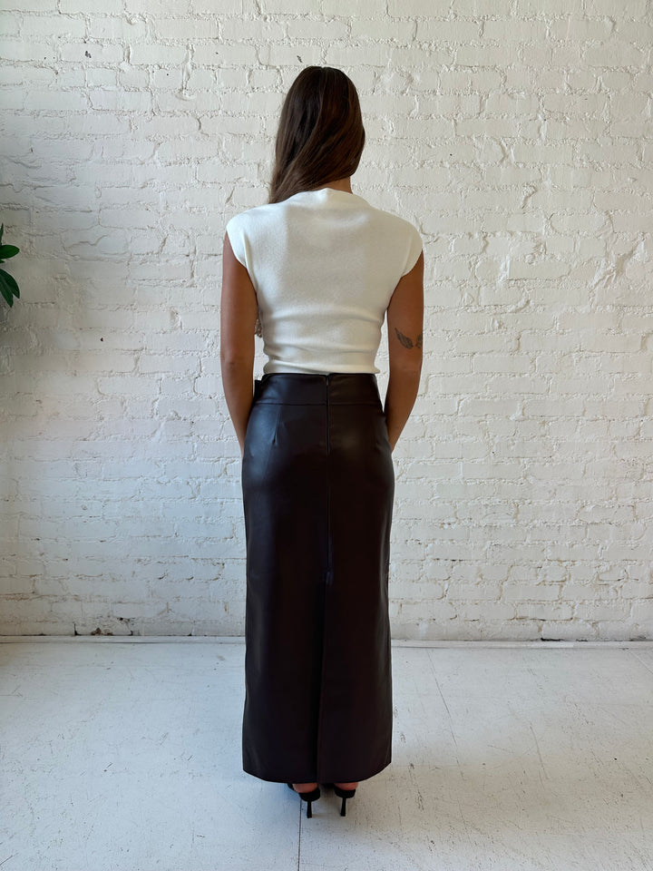 Woman wearing dark brown faux leather midi skirt with belted midsection and white cap sleeve top.