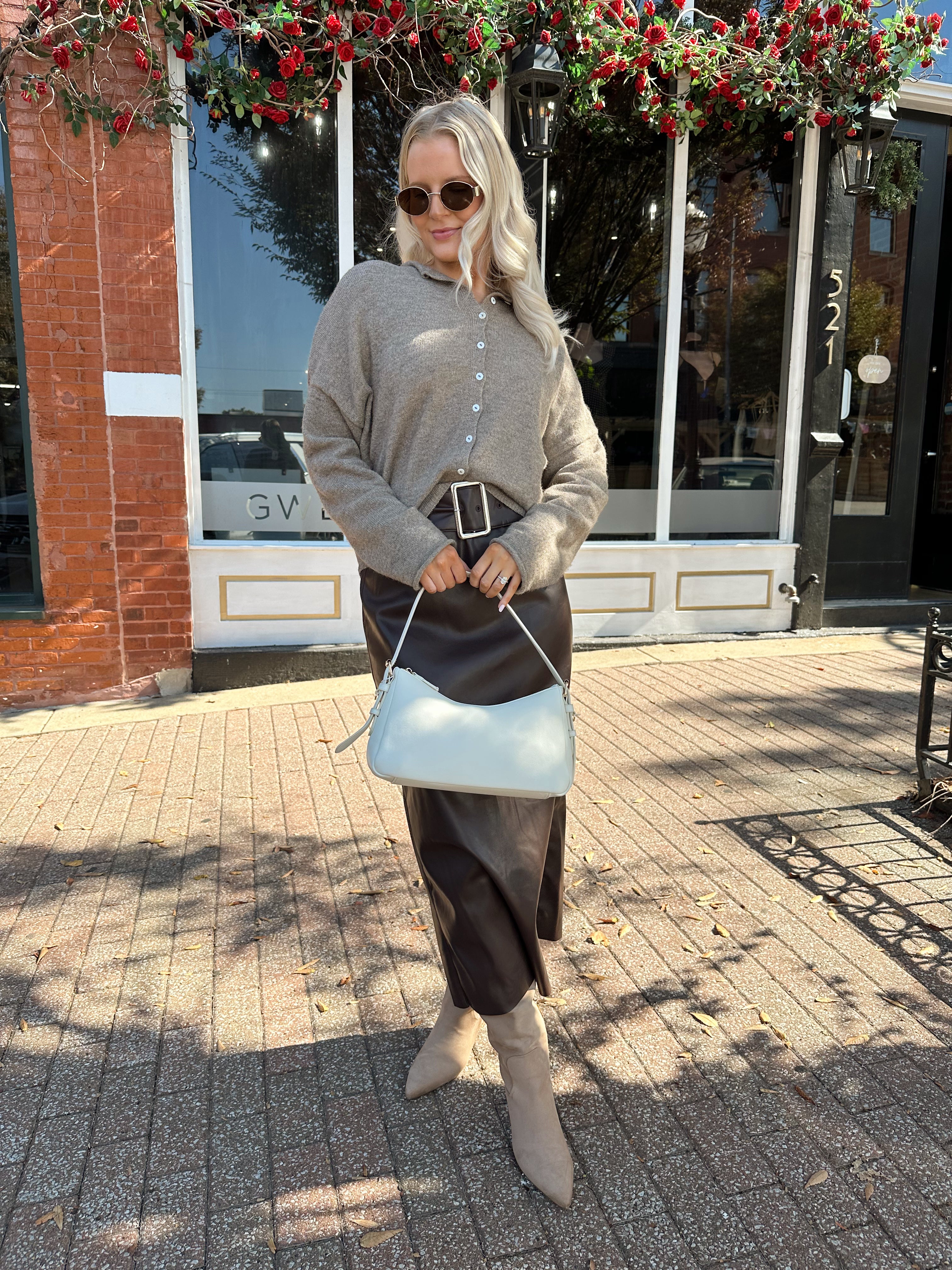 Woman wearing dark brown belted leather midi skirt with mocha knit cardigan.