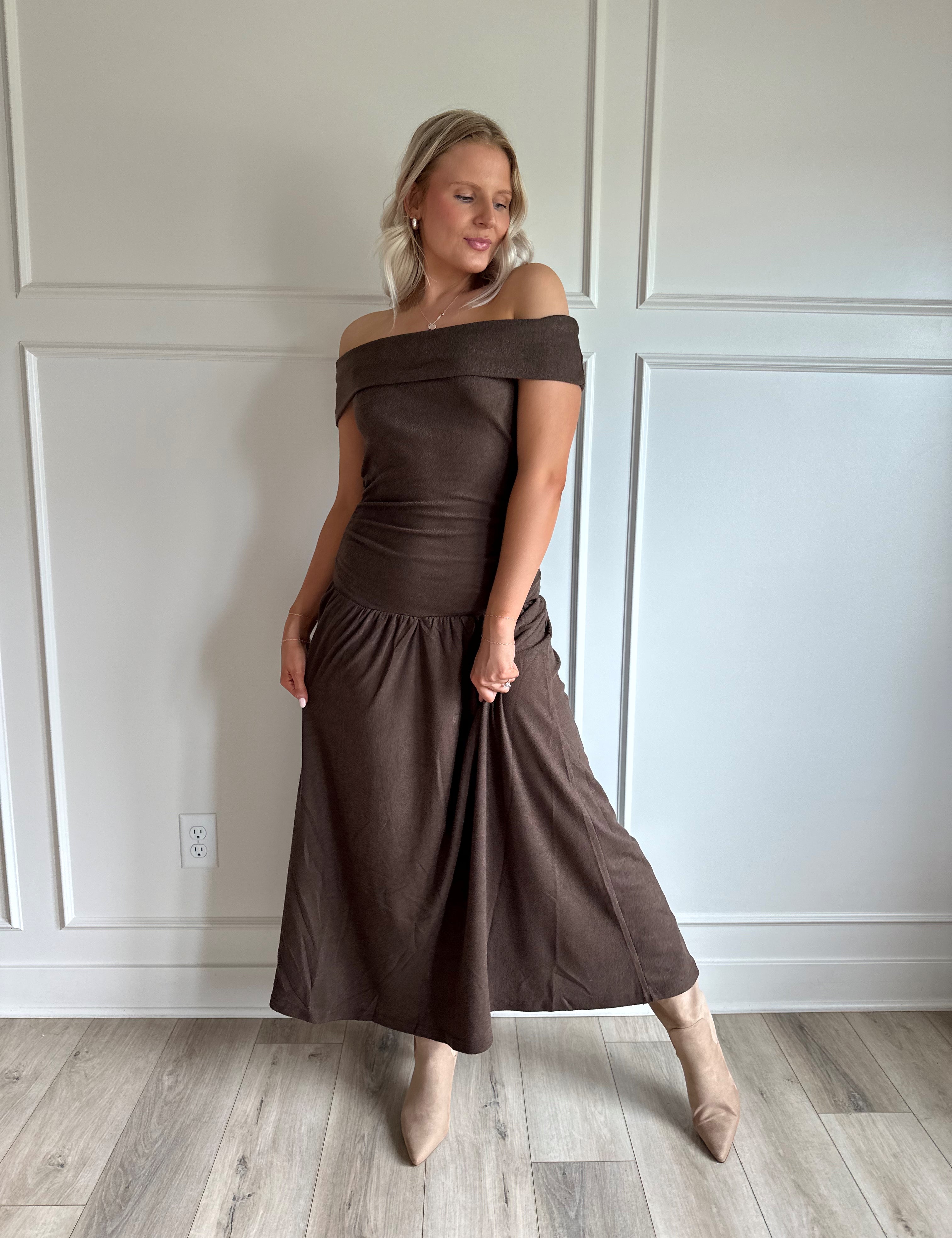 Woman wearing brown off the shoulder midi dress with drop waist and sheen. 