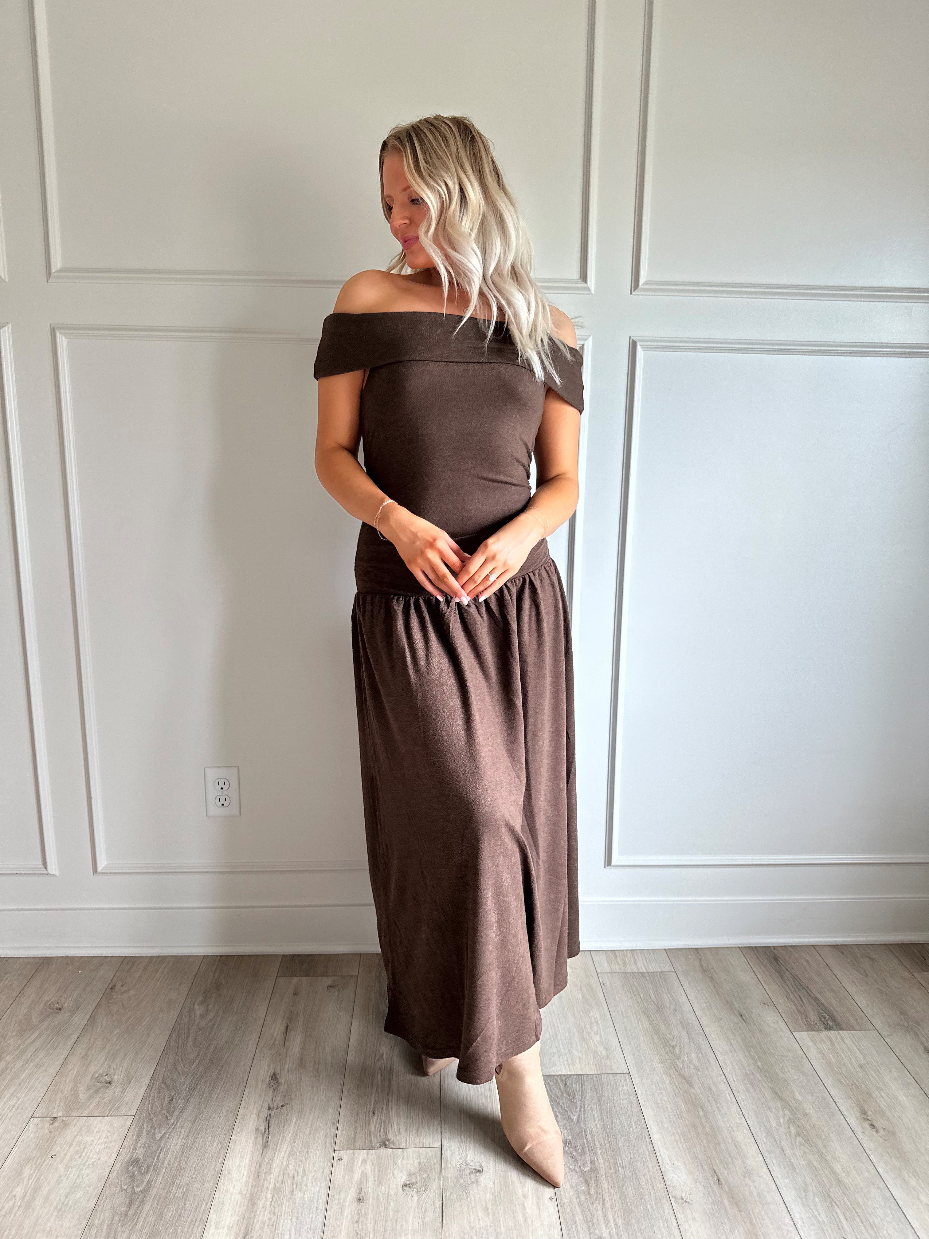 Woman wearing brown off the shoulder midi dress with drop waist and sheen. 