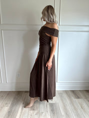 Woman wearing brown off the shoulder midi dress with drop waist and sheen. 