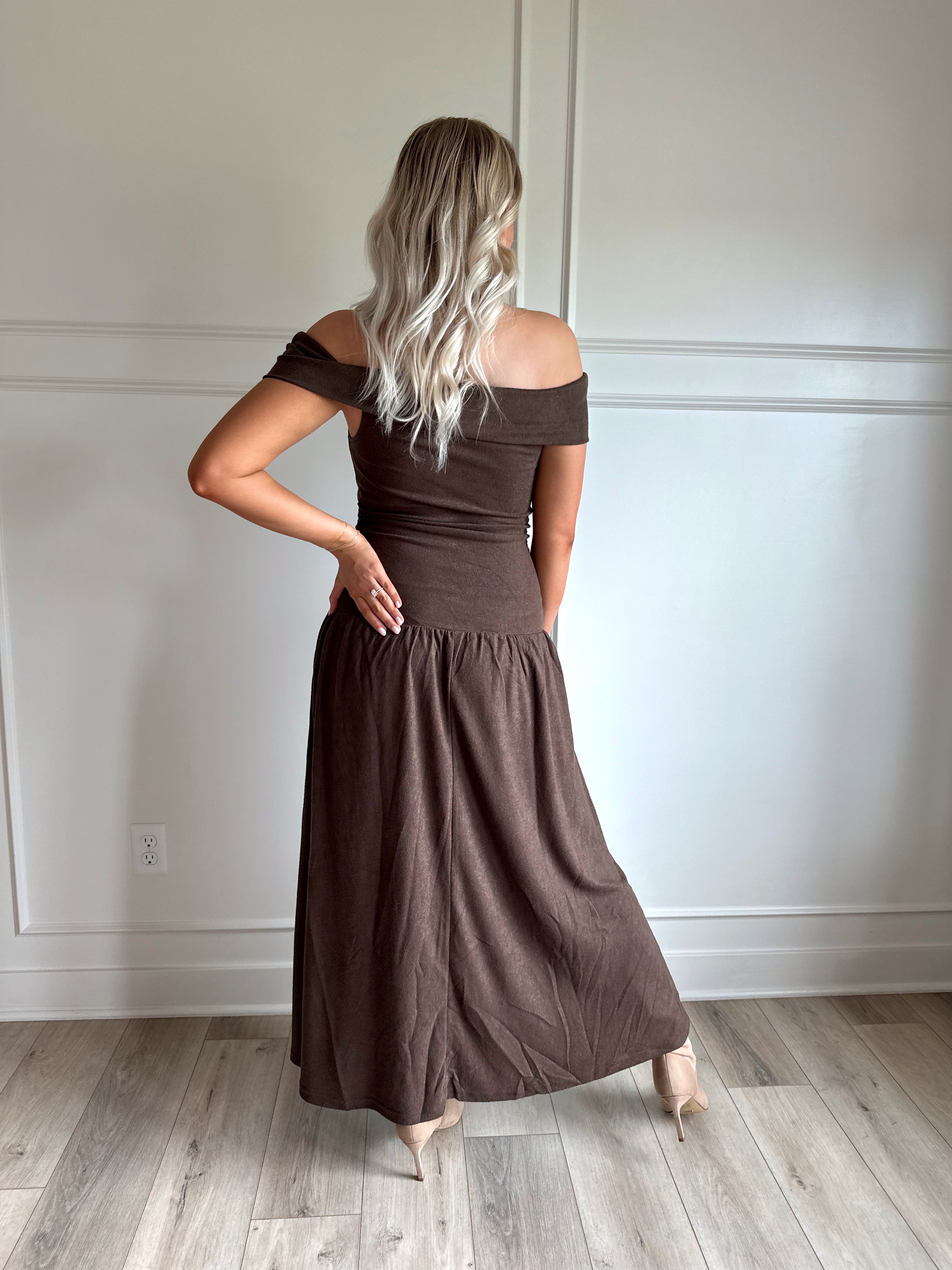 Woman wearing brown off the shoulder midi dress with drop waist and sheen. 
