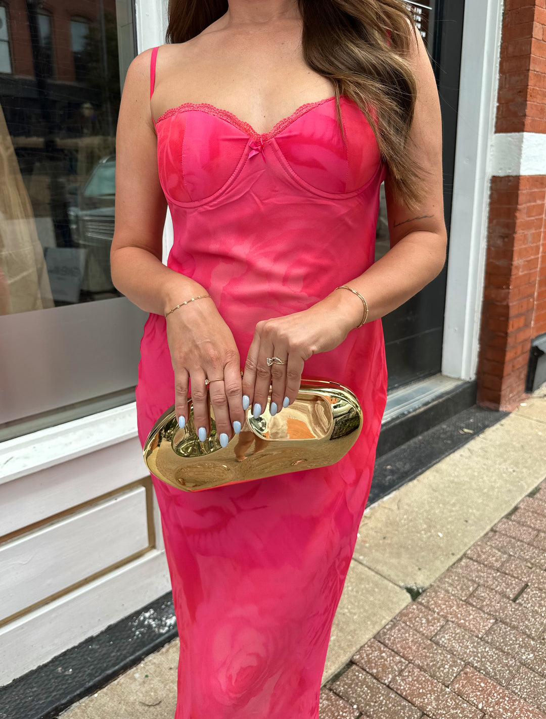 Woman wearing hot pink floral maxi dress with adjustable spaghetti straps and bustier bodice. 