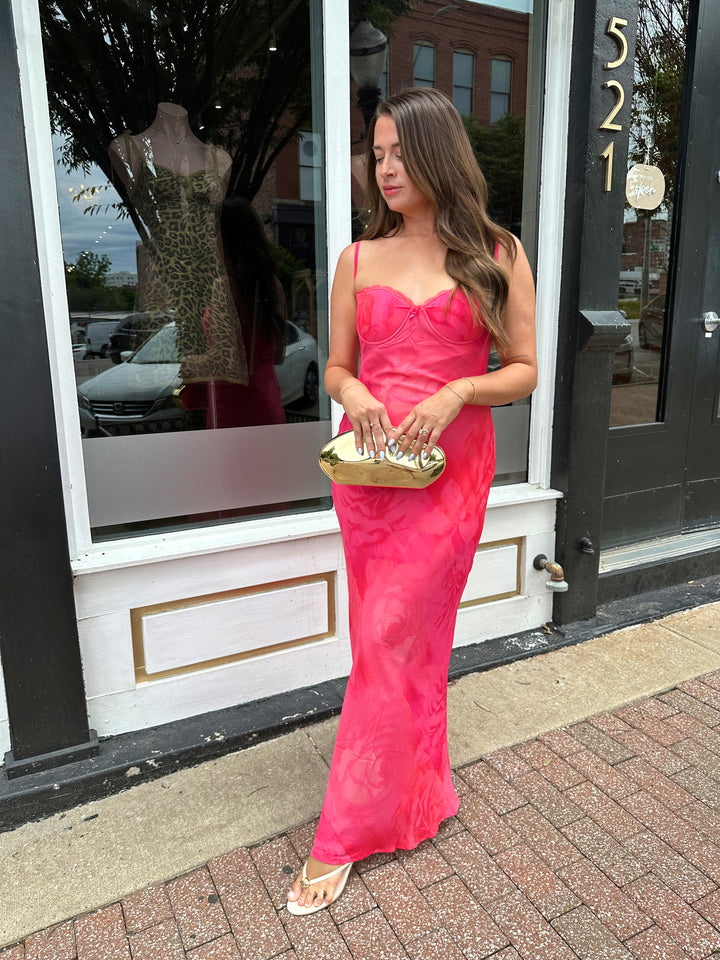 Woman wearing hot pink floral maxi dress with adjustable spaghetti straps and bustier bodice. 