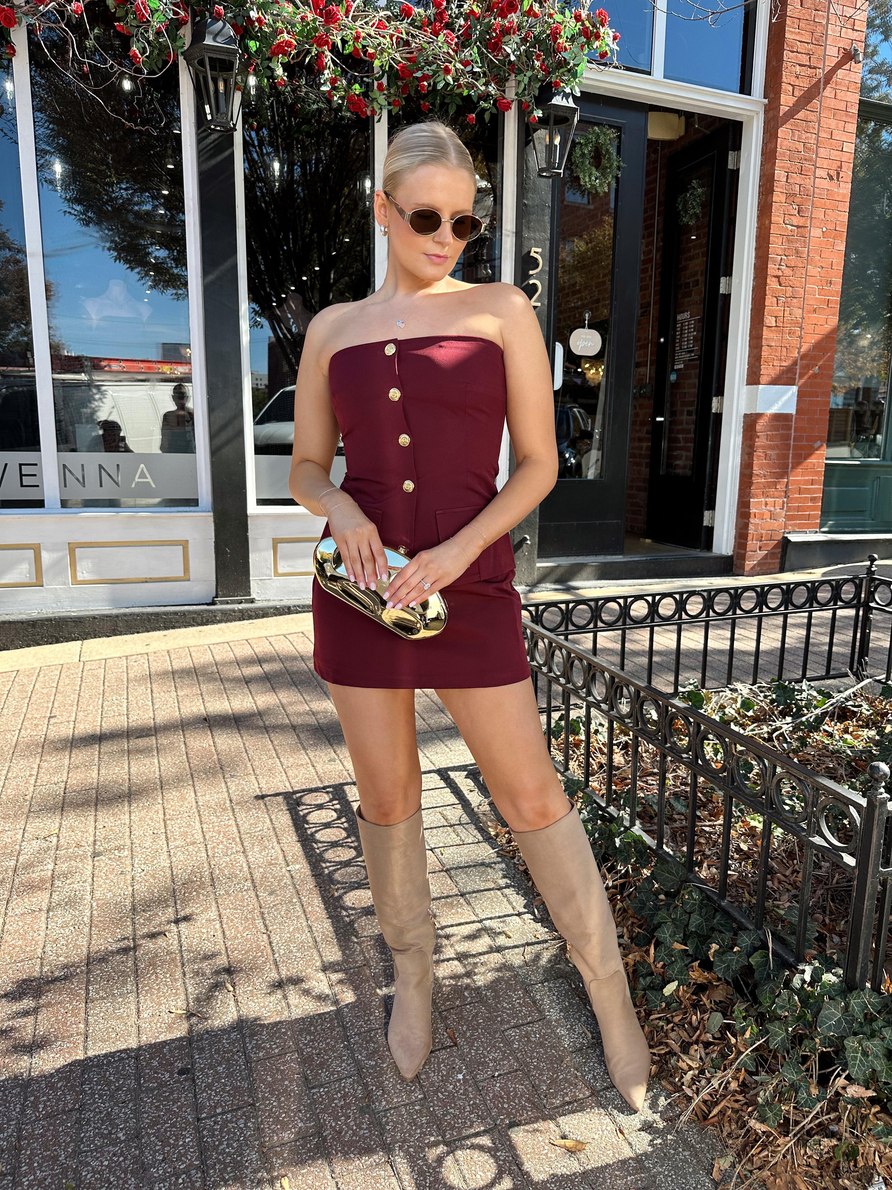 Woman wearing burgundy two piece set with gold button closure. 