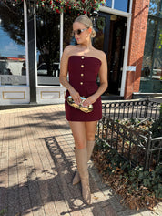 Woman wearing burgundy two piece set with gold button closure. 