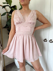 Pink satin mini dress with lace trim, v-neckline, and corset-style waist