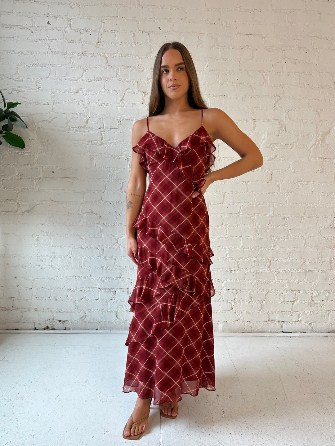 Woman wearing red plaid ruffle tiered maxi dress with adjustable spaghetti straps. 