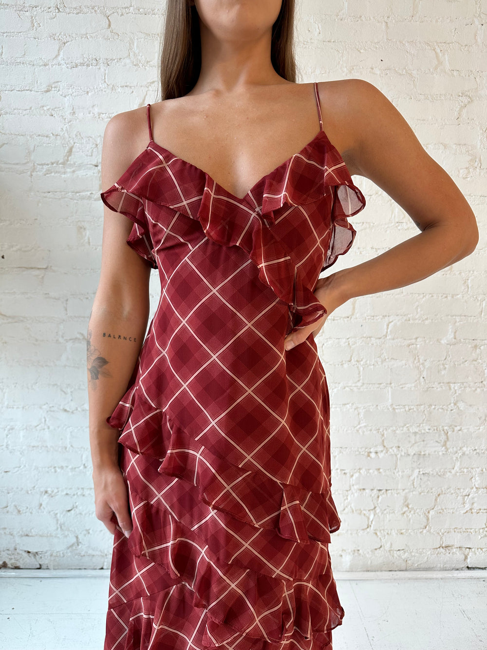 Woman wearing red plaid ruffle tiered maxi dress with adjustable spaghetti straps. 