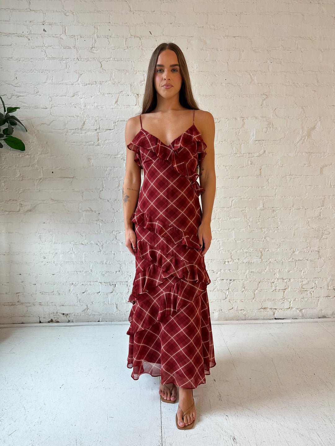 Woman wearing red plaid ruffle tiered maxi dress with adjustable spaghetti straps. 
