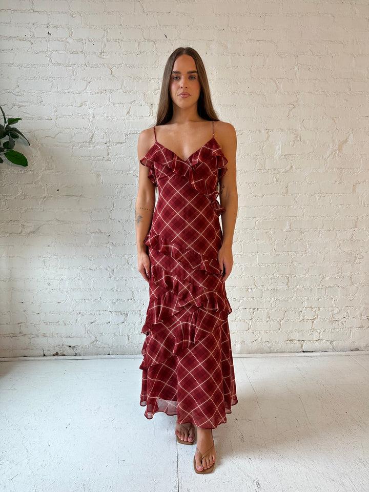 Woman wearing red plaid ruffle tiered maxi dress with adjustable spaghetti straps. 