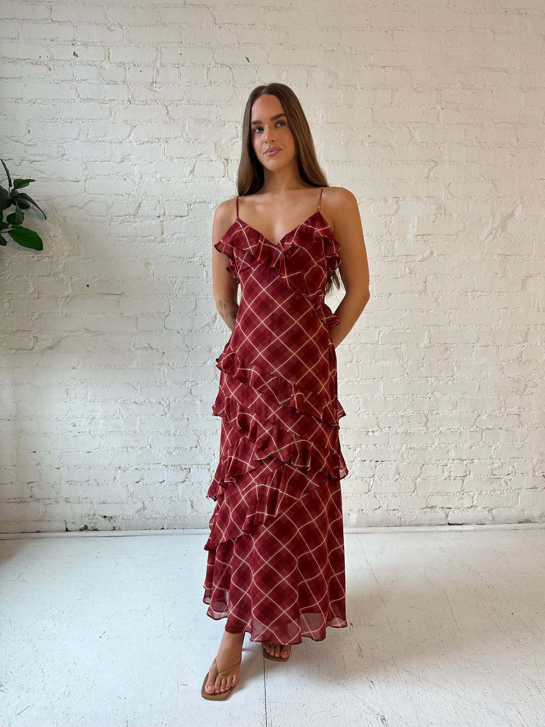 Woman wearing red plaid ruffle tiered maxi dress with adjustable spaghetti straps. 