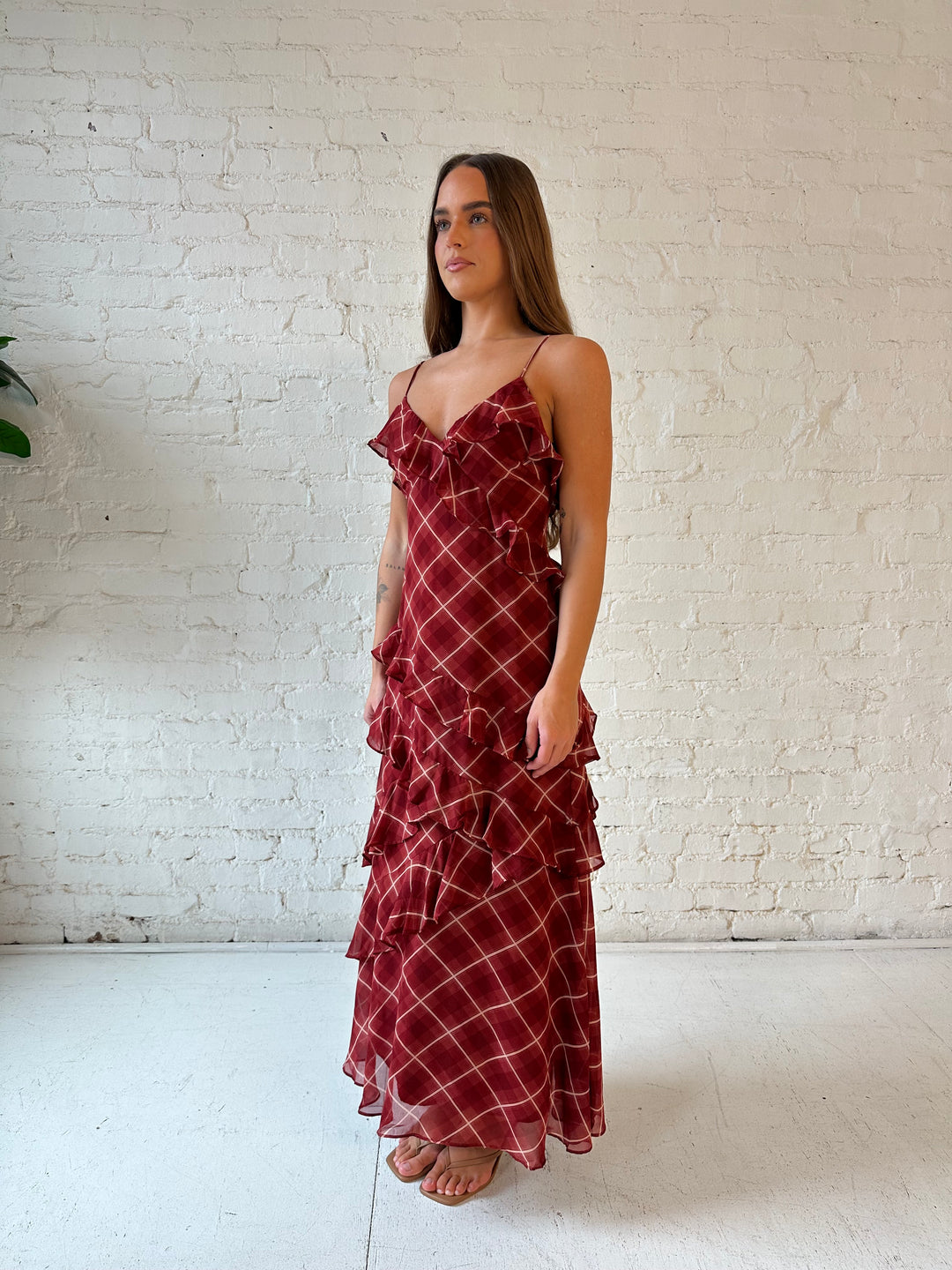 Woman wearing red plaid ruffle tiered maxi dress with adjustable spaghetti straps. 