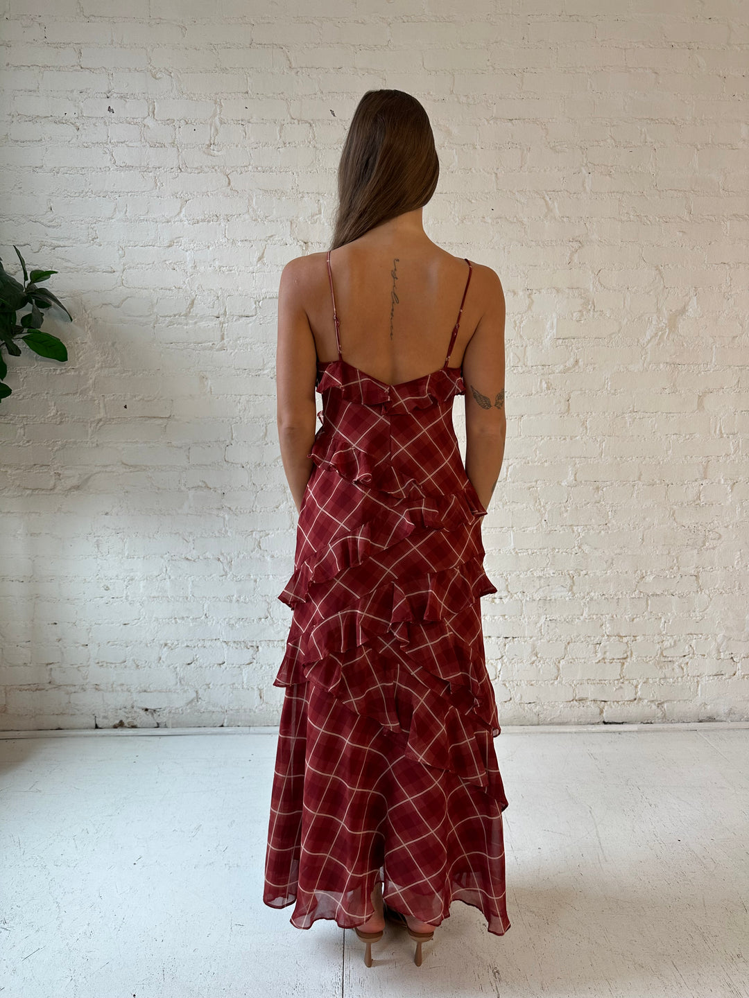 Woman wearing red plaid ruffle tiered maxi dress with adjustable spaghetti straps. 