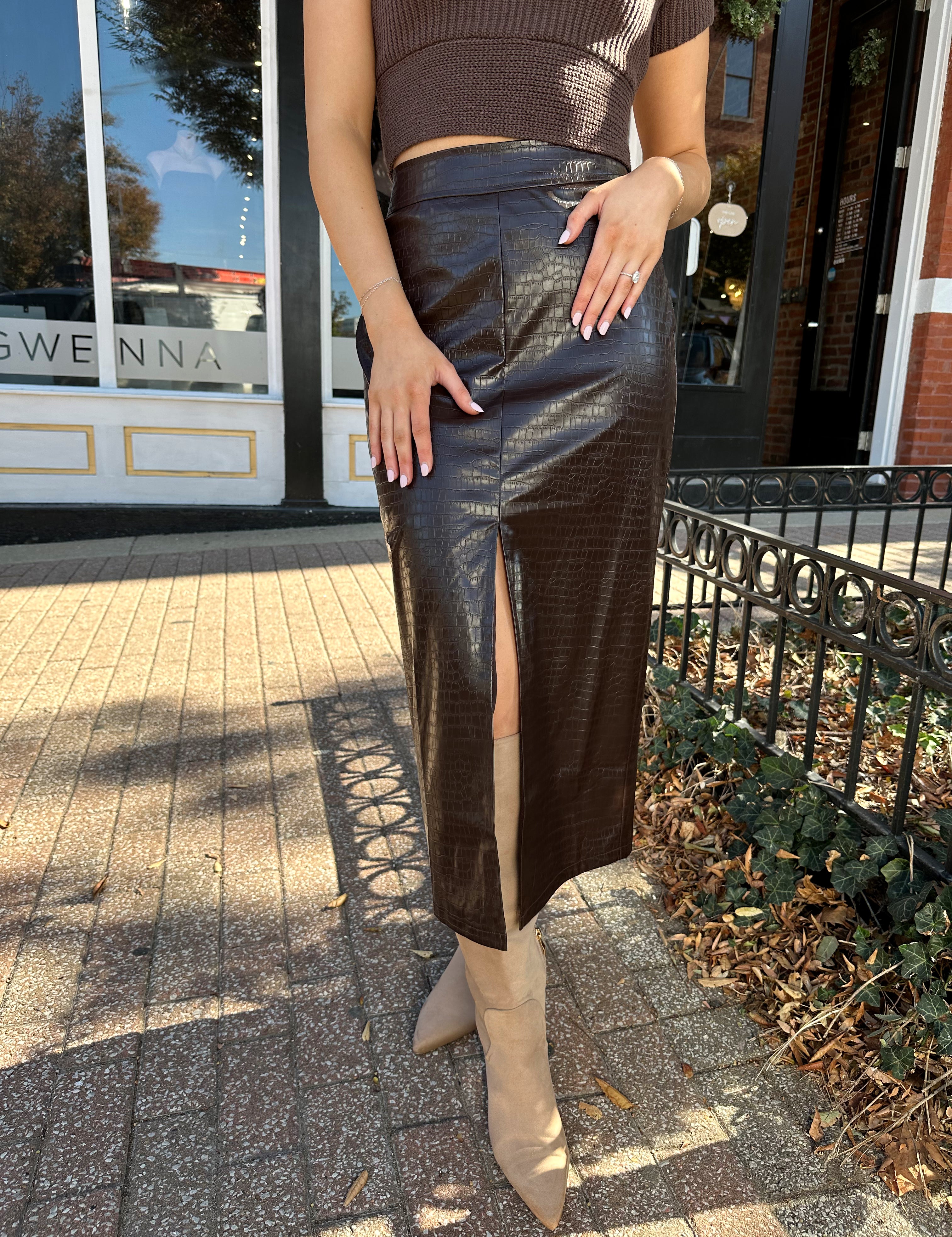 Woman wearing brown croc leather midi skirt with front slit. 