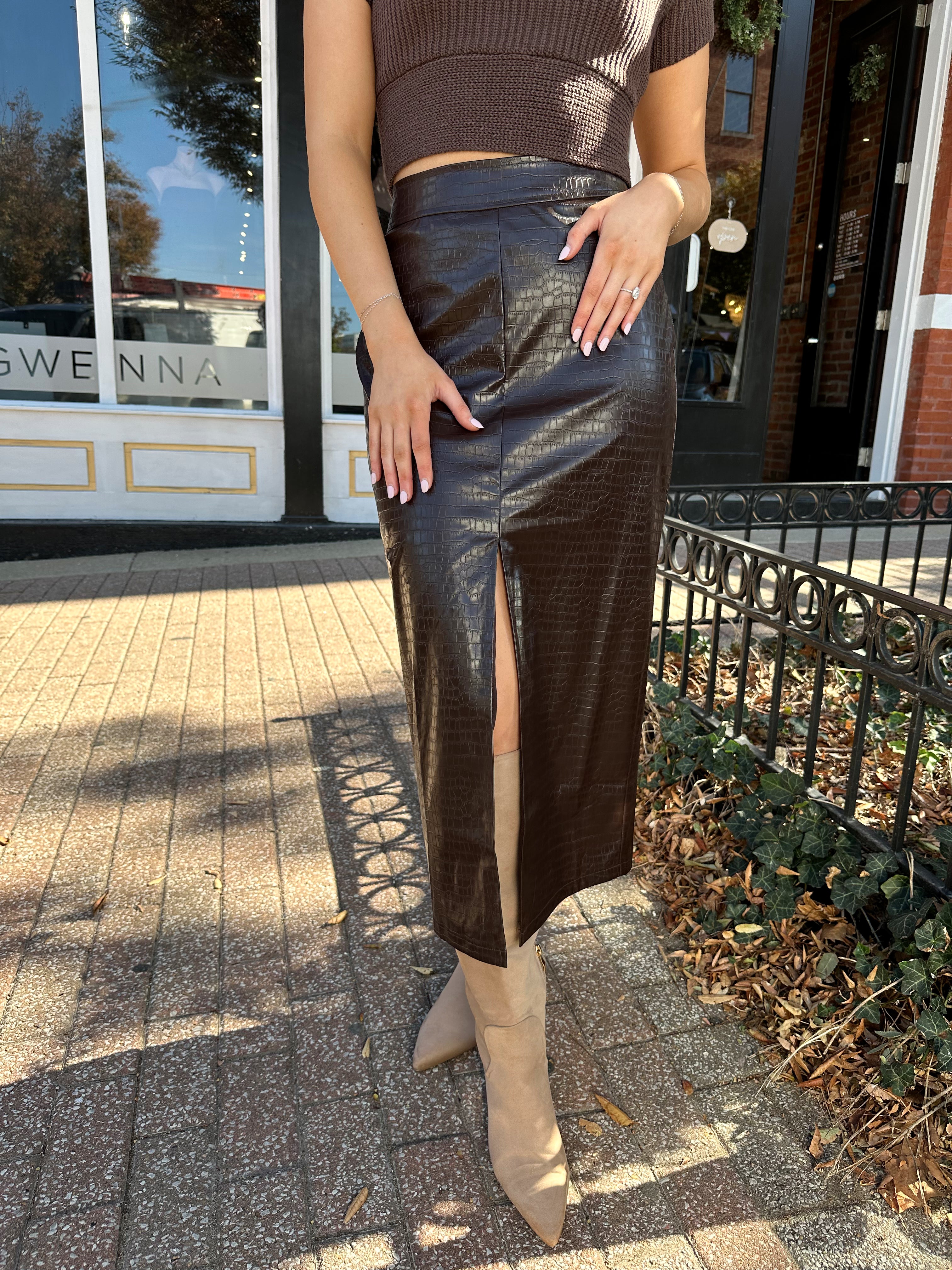 Woman wearing brown croc leather midi skirt with front slit. 