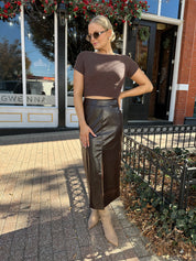 Woman wearing brown croc leather midi skirt with front slit. 