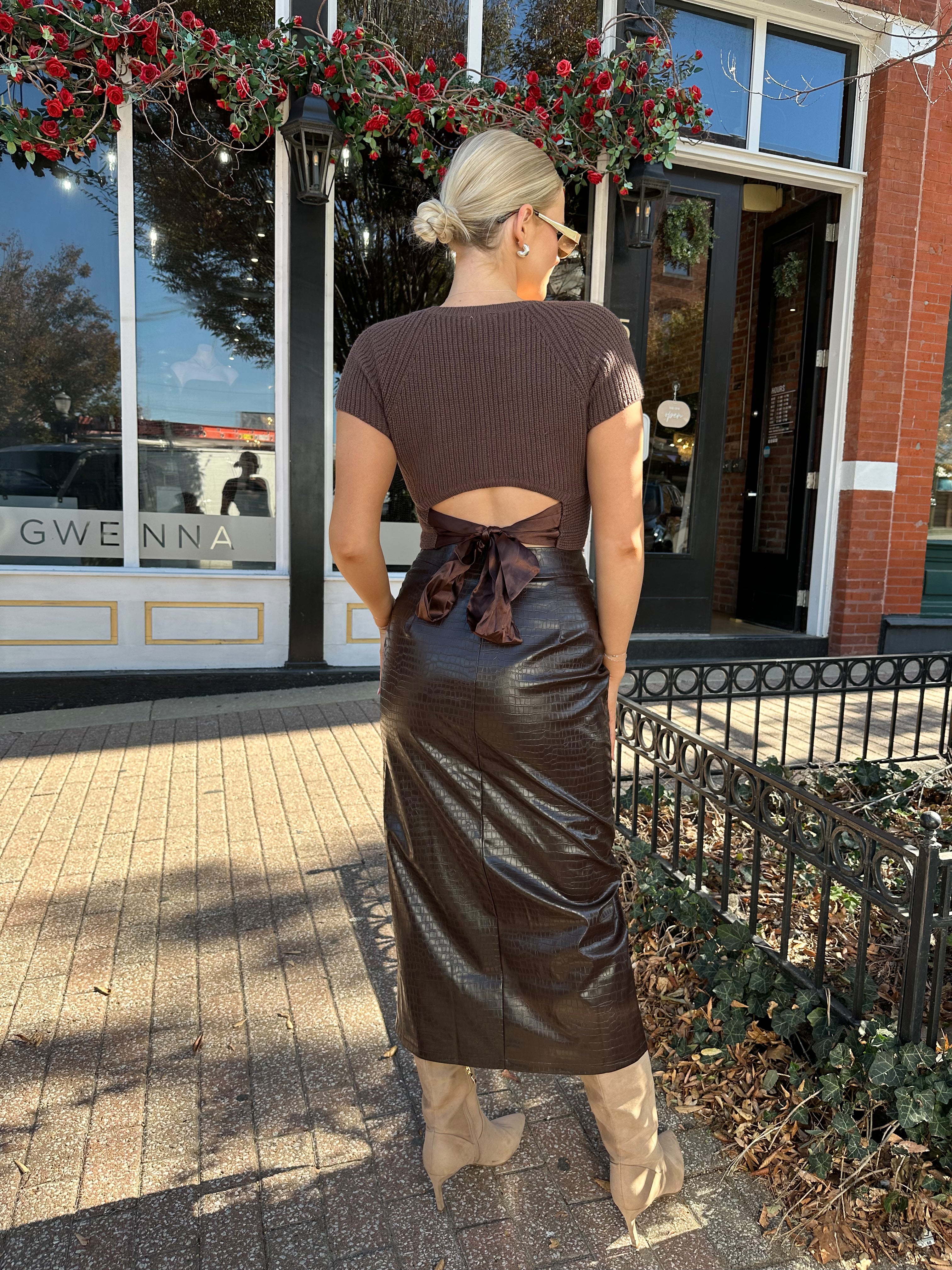 Woman wearing brown croc leather midi skirt with front slit. 