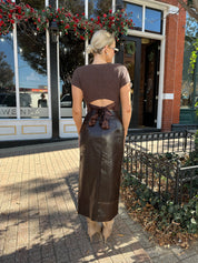 Woman wearing brown croc leather midi skirt with front slit. 
