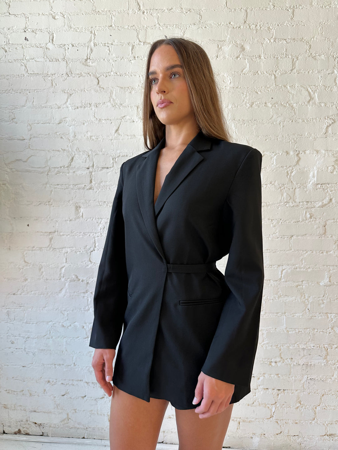 Woman wearing black oversized blazer with wrap tie detail.