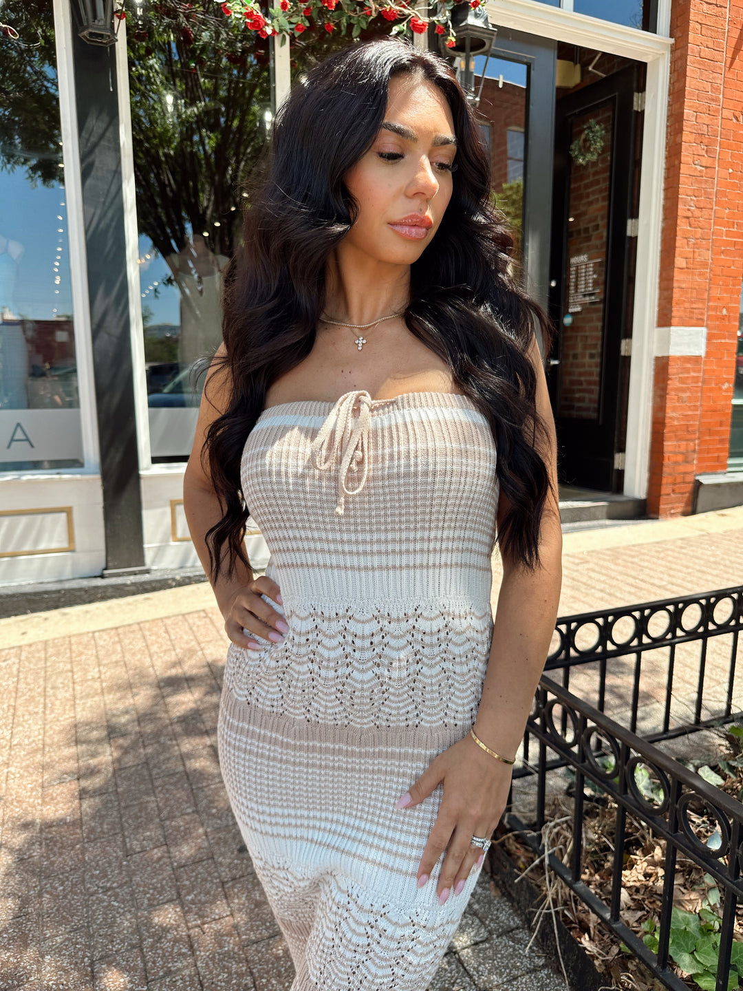 Woman wearing tan and white crochet striped maxi dress with tie neckline detail.