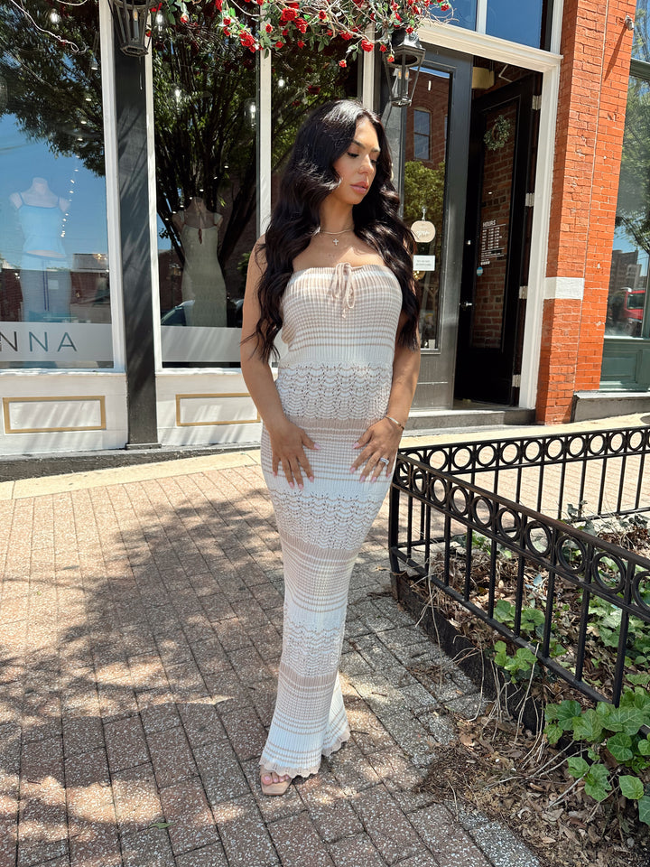 Woman wearing tan and white crochet striped maxi dress with tie neckline detail.