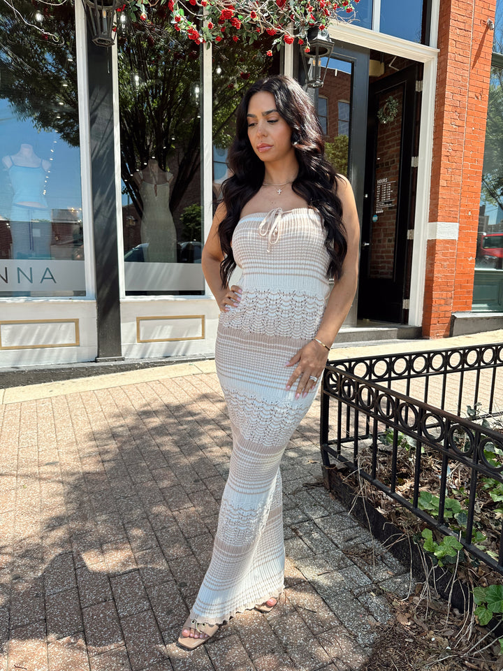 Woman wearing tan and white crochet striped maxi dress with tie neckline detail.