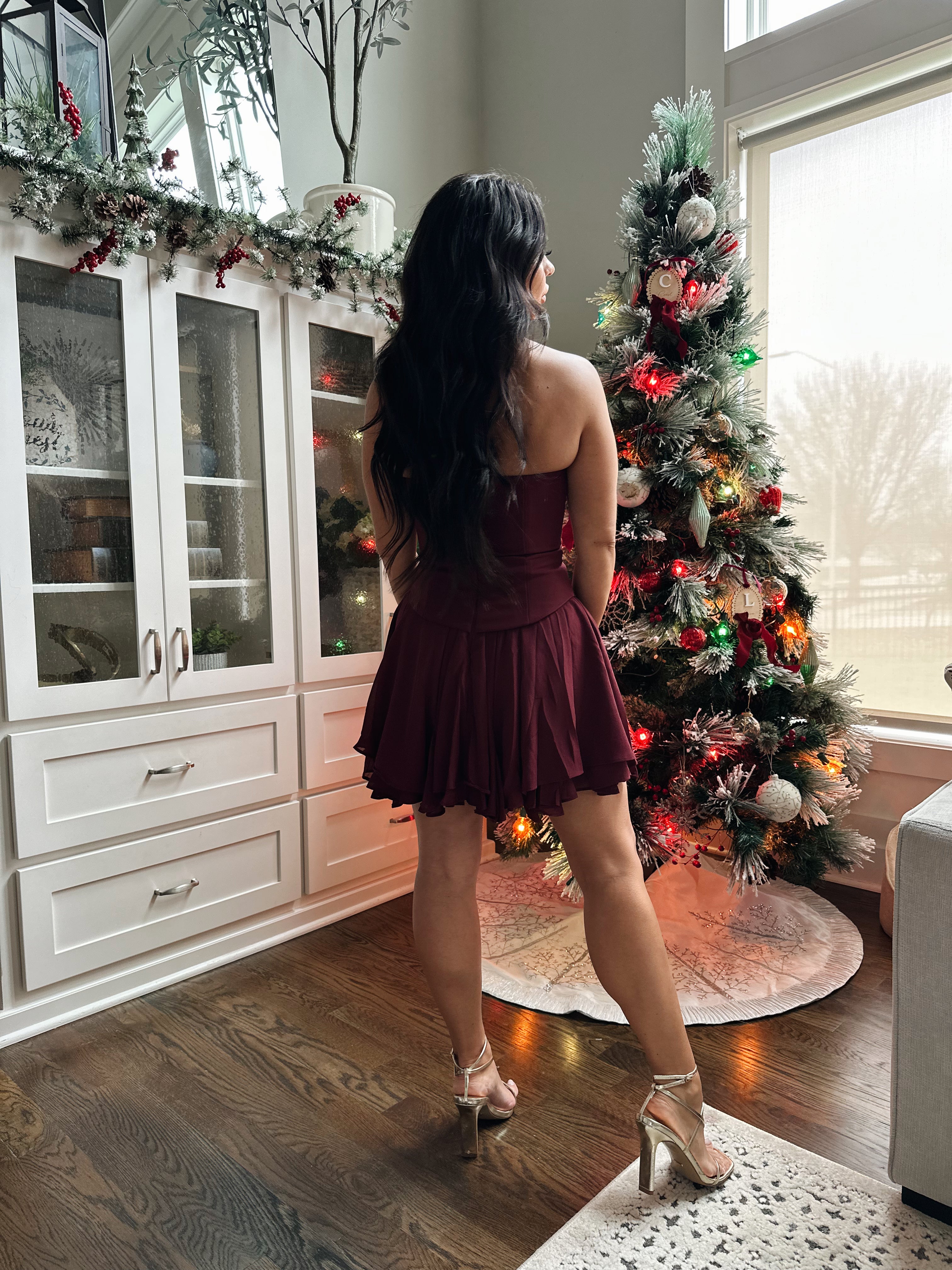 Woman wearing burgundy strapless mini dress with tiered skirt. 