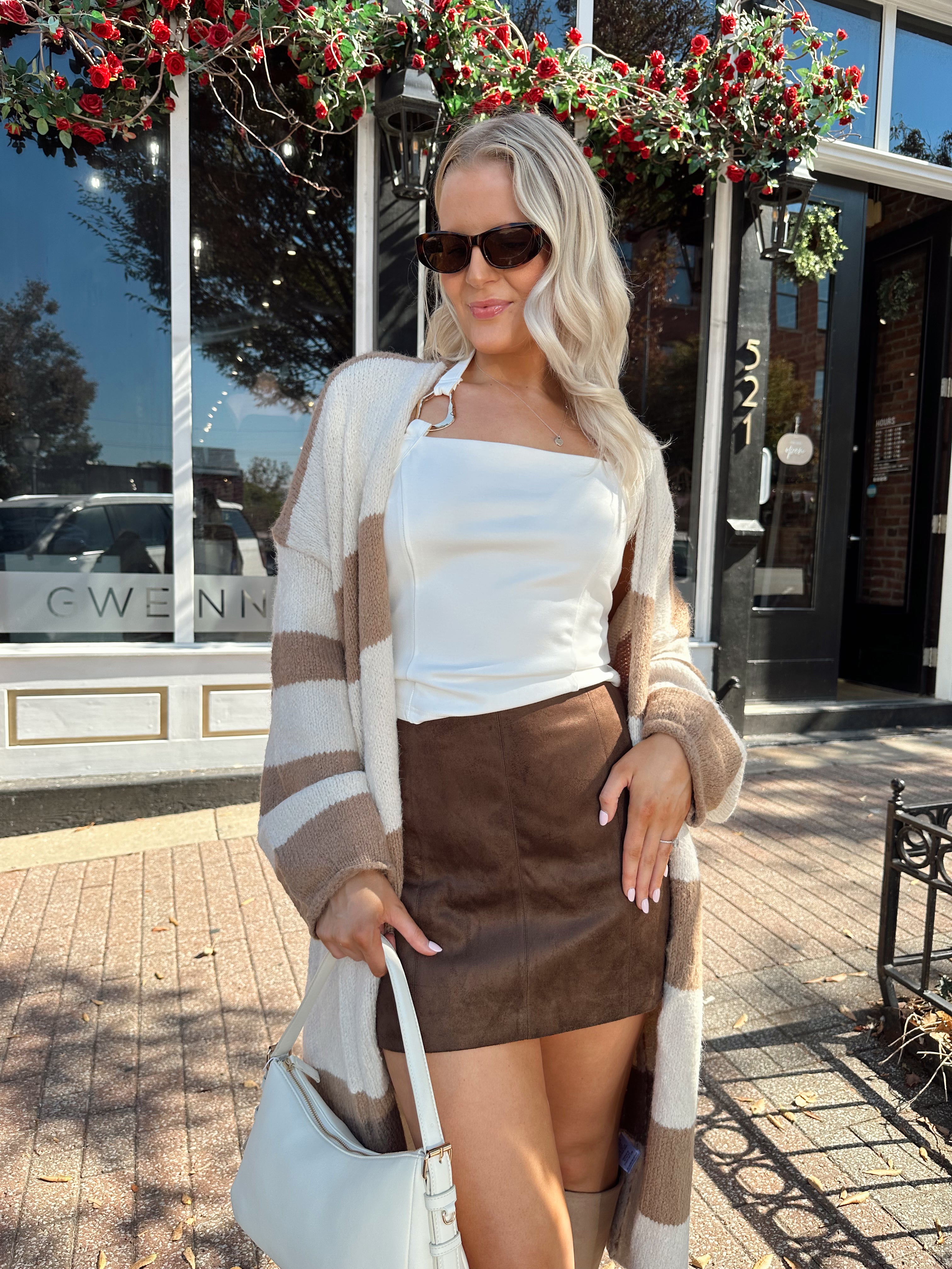 Woman wearing brown and cream striped cardigan with functional pockets.