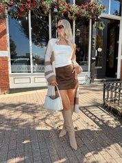 Woman wearing brown and cream striped cardigan with functional pockets.