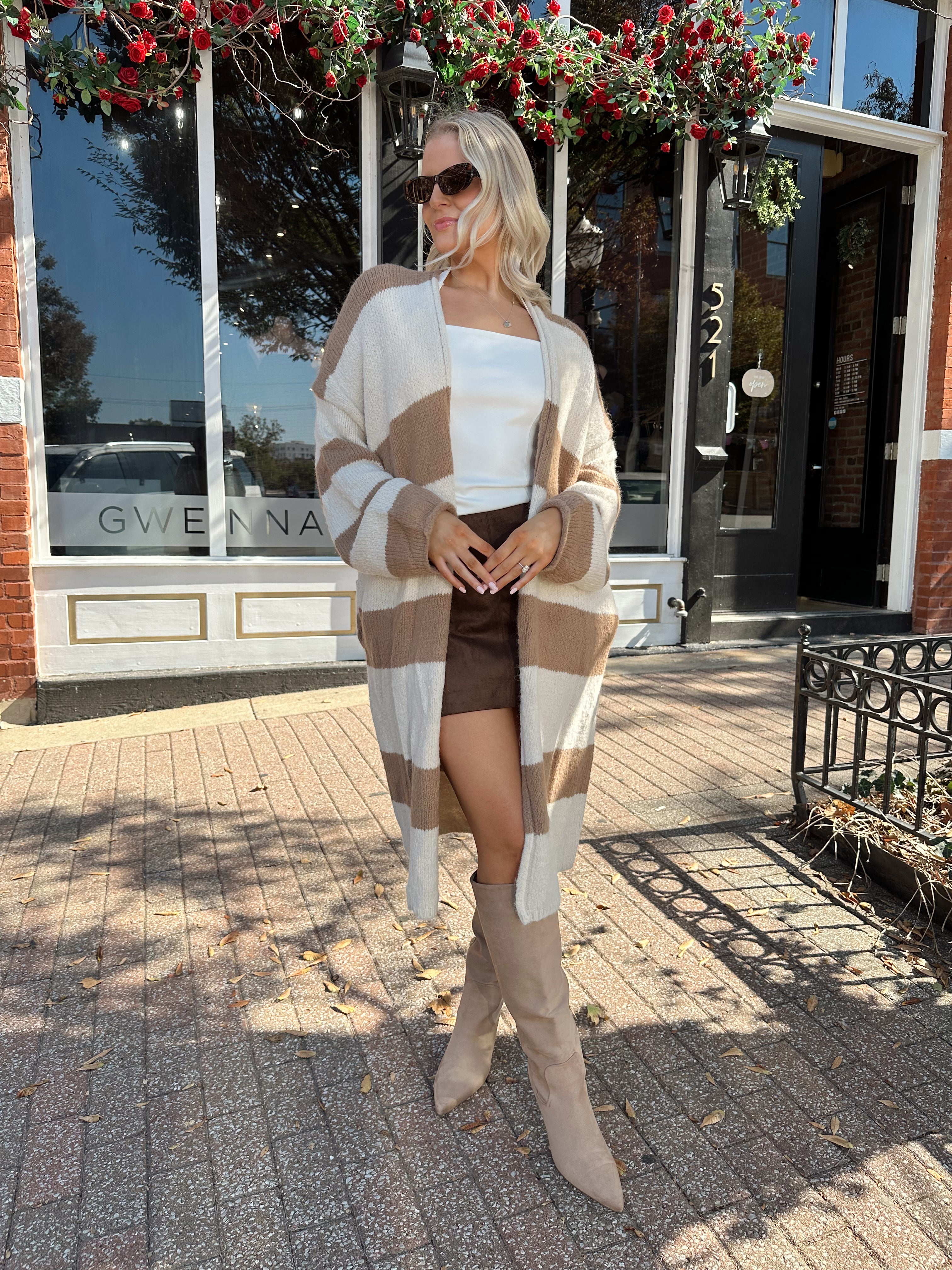 Woman wearing brown and cream striped cardigan with functional pockets.