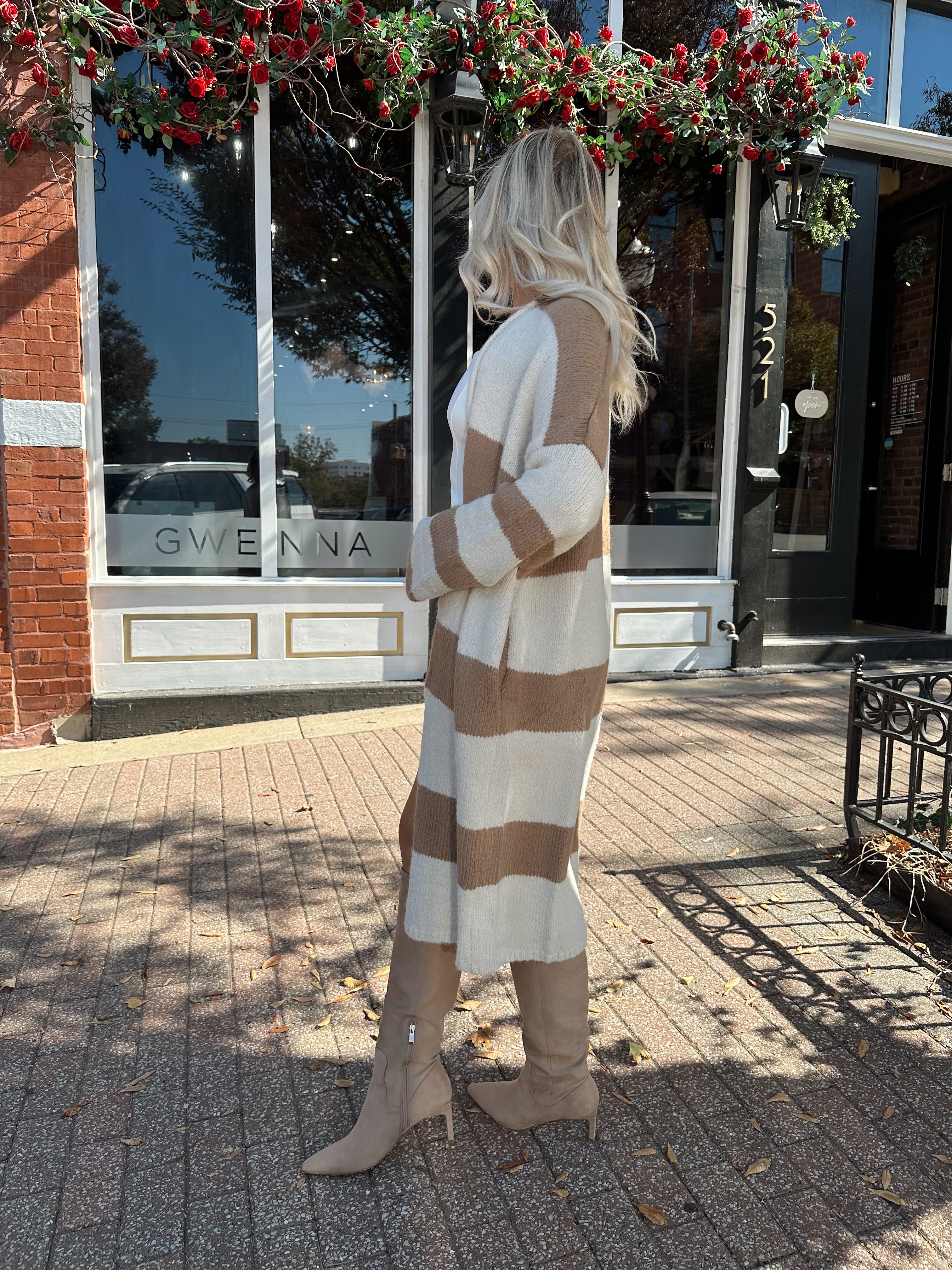 Woman wearing brown and cream striped cardigan with functional pockets.