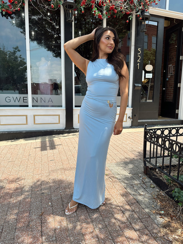 Woman wearing soft light blue two piece maxi skirt set with ring and bead detailing. 