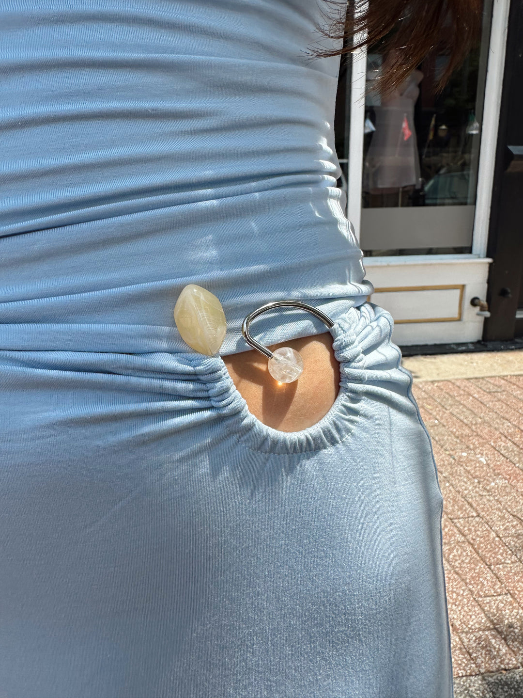 Woman wearing soft light blue two piece maxi skirt set with ring and bead detailing. 