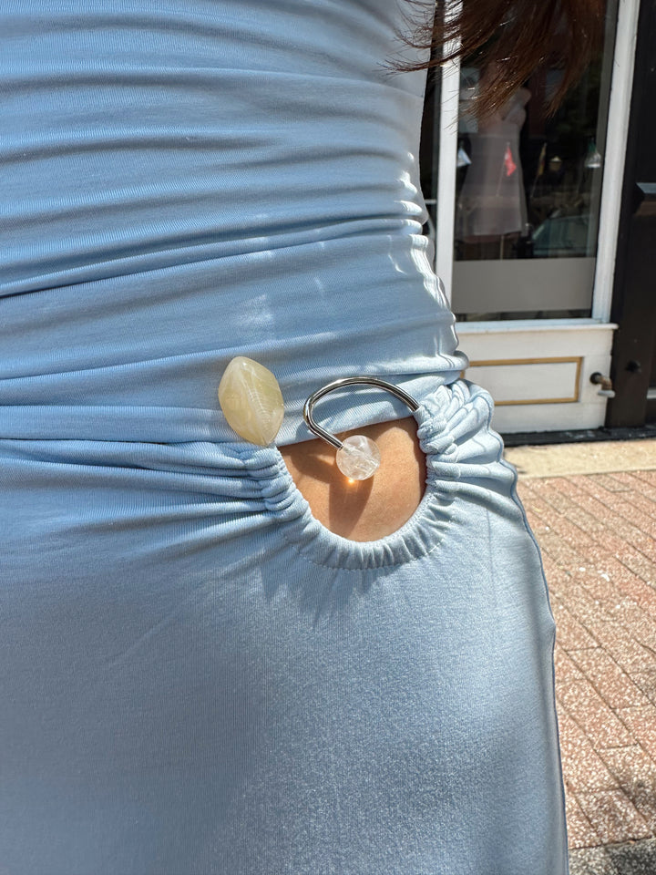 Woman wearing soft light blue two piece maxi skirt set with ring and bead detailing. 