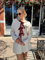 Woman wearing cream front tie cardigan with burgundy stitch detailing. 
