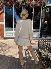 Woman wearing cream front tie cardigan with burgundy stitch detailing. 